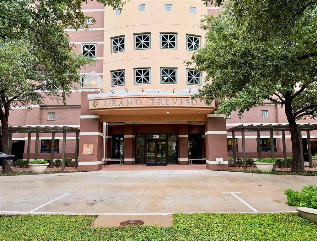 330 Las Colinas Boulevard E, #1006, Irving, TX 75039 Building exterior with a prominent arched entrance, dual automatic glass doors, and a decorative signage above