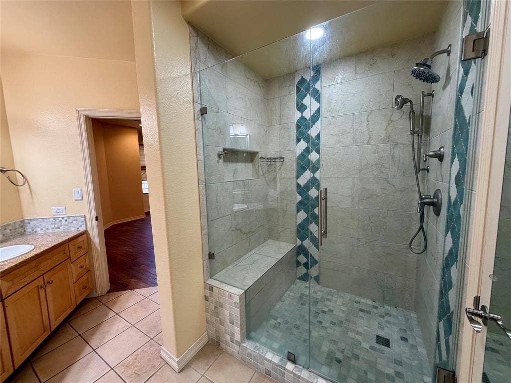 330 Las Colinas Boulevard E, #1006, Irving, TX 75039 Glass-enclosed shower with a built-in bench, dual shower heads, and decorative tile accents