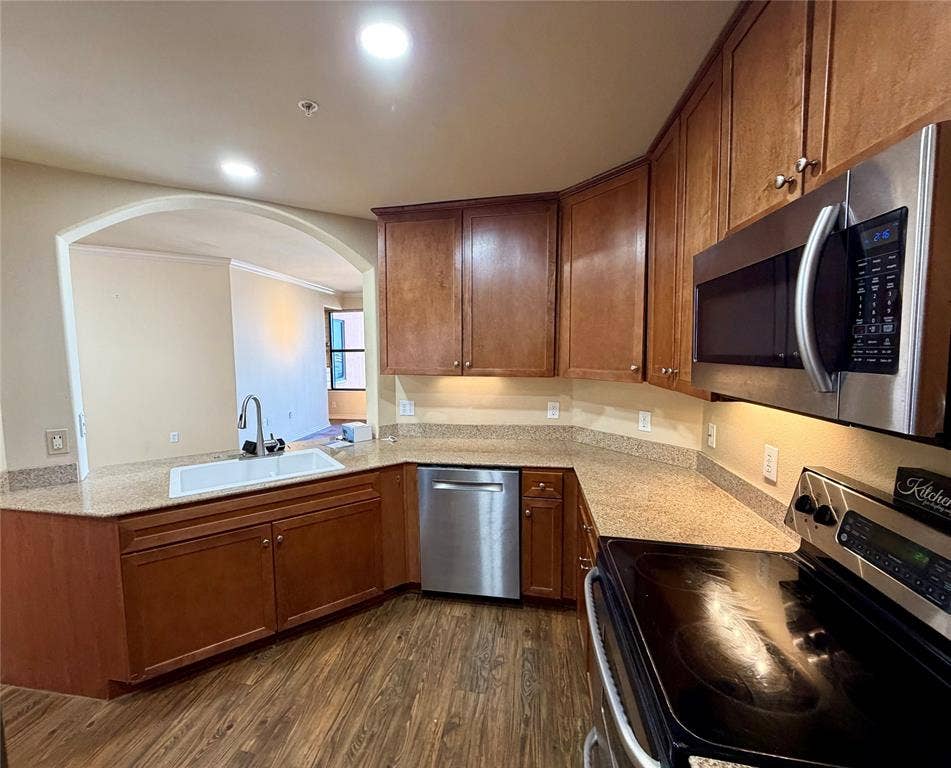 330 Las Colinas Boulevard E, #1006, Irving, TX 75039 Kitchen featuring wood-finish cabinetry, stainless steel appliances, granite countertops, an undermount sink, and recessed lighting