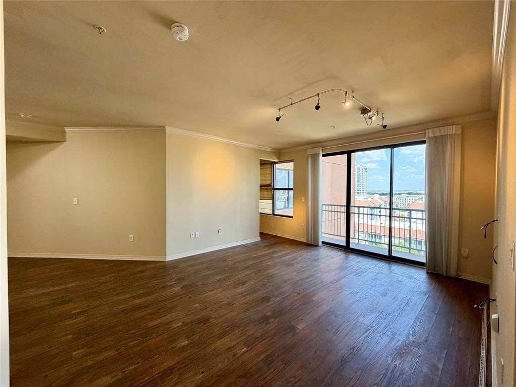 330 Las Colinas Boulevard E, #1006, Irving, TX 75039 Expansive living area featuring wood-finish flooring, track lighting, crown molding, and large sliding glass doors opening to an exterior balcony