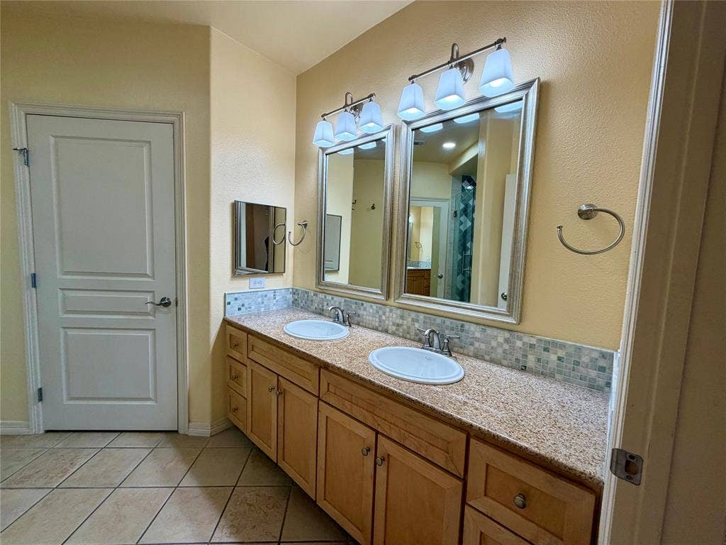 330 Las Colinas Boulevard E, #1006, Irving, TX 75039 Double vanity with integrated sinks, mosaic tile backsplash, light wood-finish cabinetry, and tiled flooring