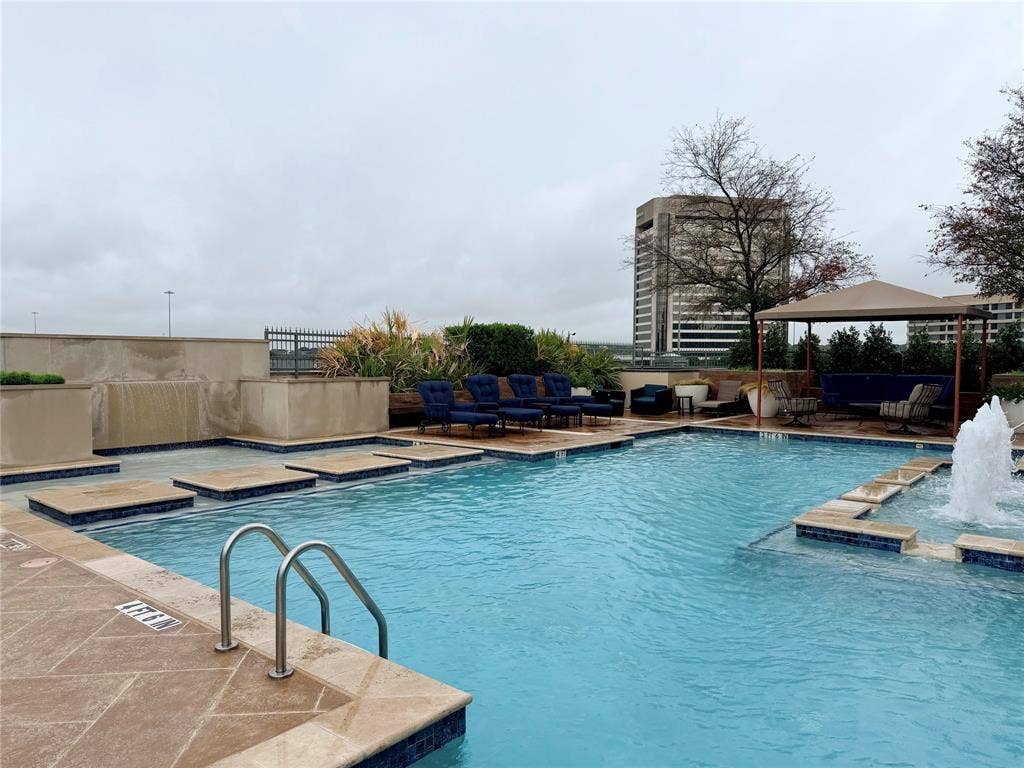 330 Las Colinas Boulevard E, #1006, Irving, TX 75039 Expansive pool area featuring a built-in waterfall, integrated fountain, tiled steps, and a shaded cabana structure