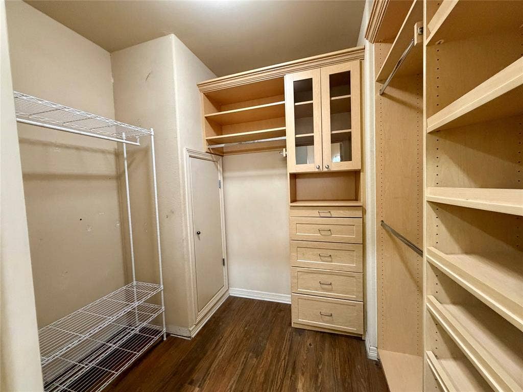 330 Las Colinas Boulevard E, #1006, Irving, TX 75039 Closet featuring wood-finish flooring, built-in cabinetry with glass-front doors, multiple drawers, and adjustable shelving units