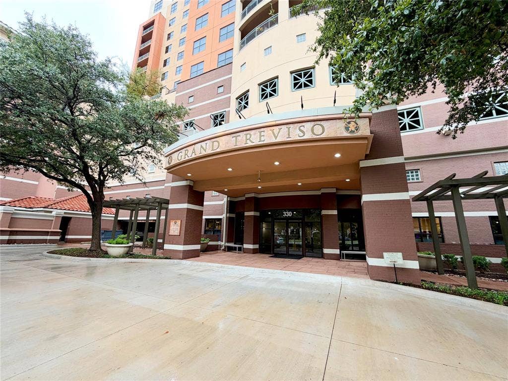 330 Las Colinas Boulevard E, #1006, Irving, TX 75039 Arched entryway with a prominent sign, multiple windows with decorative grilles, and a curved drive