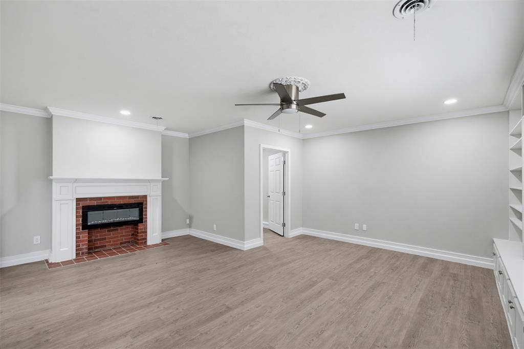 1312 E Mitchell Street, Arlington, TX 76010 Wood-finish flooring, white crown molding, brick fireplace with mantel, recessed lighting, and ceiling fan
