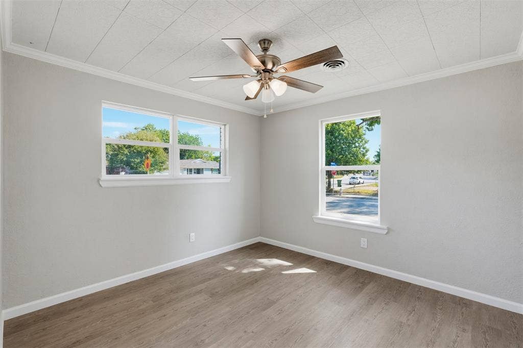 1312 E Mitchell Street, Arlington, TX 76010 Room featuring two windows, wood-finish flooring, a ceiling fan with integrated lighting, and crown molding