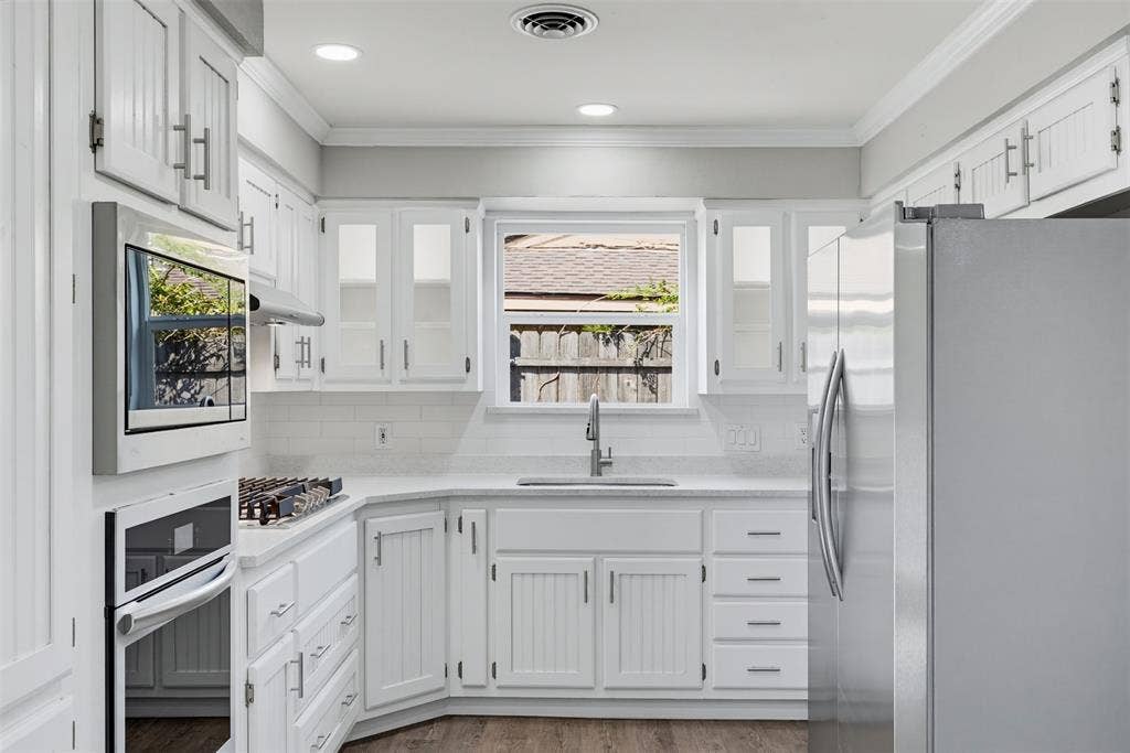1312 E Mitchell Street, Arlington, TX 76010 White cabinetry with brushed nickel hardware, stainless steel appliances, and a built-in microwave