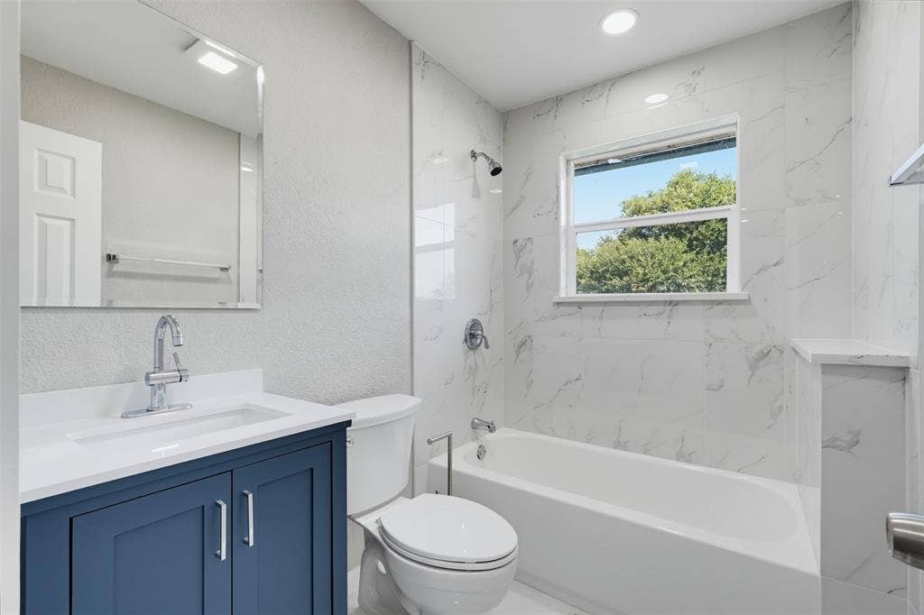 1312 E Mitchell Street, Arlington, TX 76010 White tiled shower surround with built-in niche, white bathtub, and recessed lighting