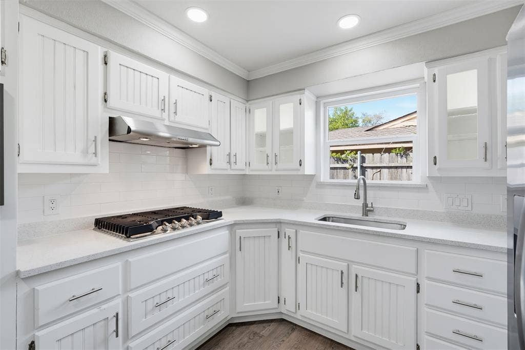 1312 E Mitchell Street, Arlington, TX 76010 White cabinetry with beadboard paneling, light-toned countertops, and a white subway tile backsplash