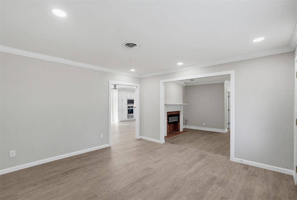1312 E Mitchell Street, Arlington, TX 76010 Recessed lighting, crown molding, wood-finish flooring, brick fireplace with white mantel, white cabinetry
