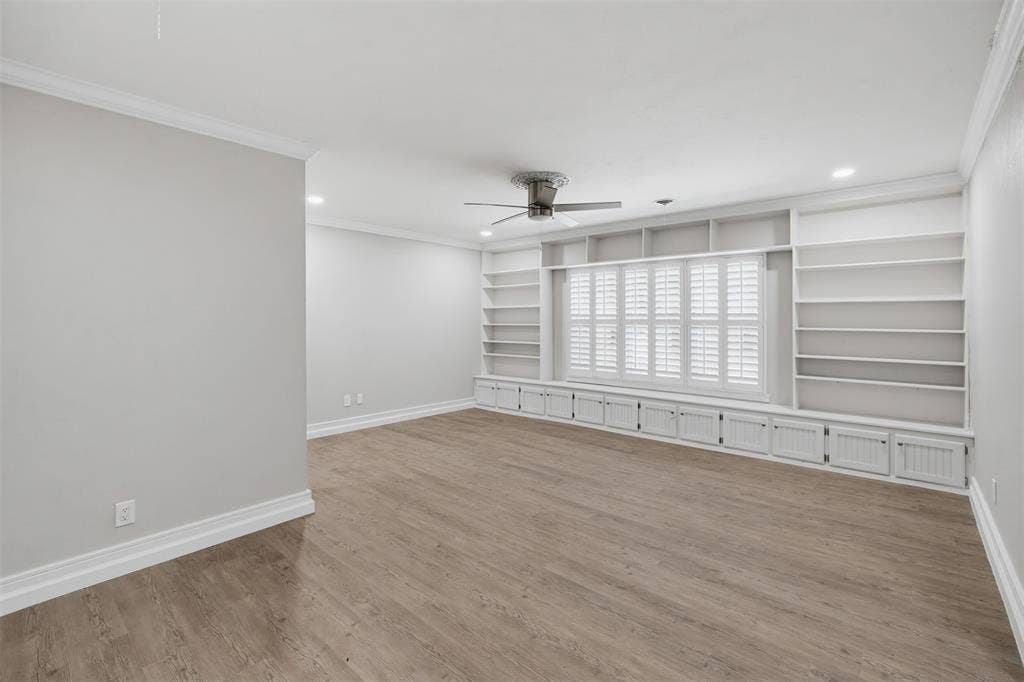 1312 E Mitchell Street, Arlington, TX 76010 Wood-finish flooring, crown molding, a ceiling fan, recessed lighting, and built-in shelving with lower cabinetry