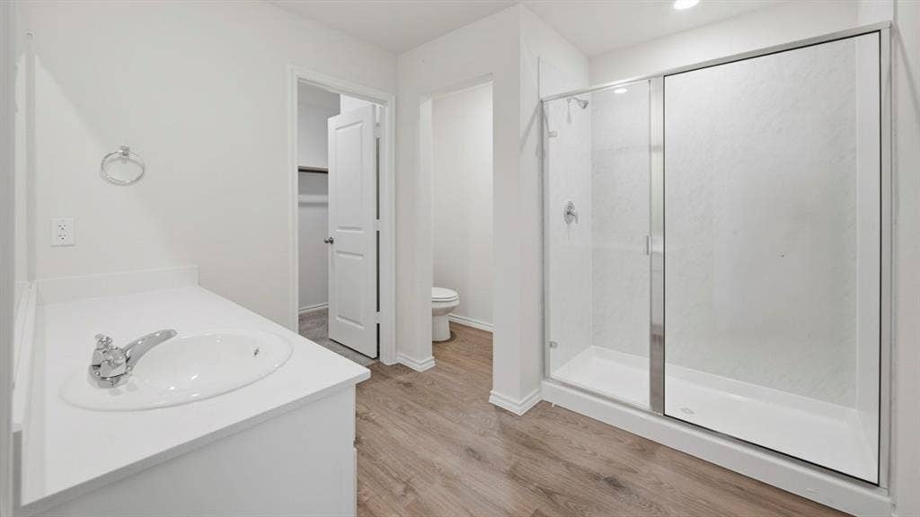 1916 Freeman Street, Tyler, TX 75704 Contemporary bathroom featuring a spacious glass-enclosed shower, white vanity with integrated sink, chrome fixtures, recessed lighting, and wood-finish flooring