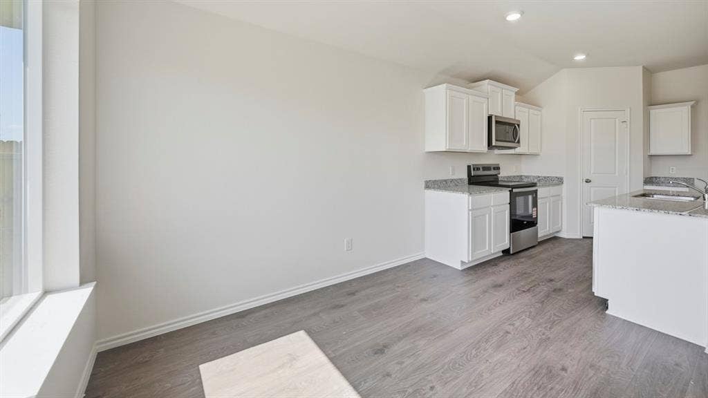 1916 Freeman Street, Tyler, TX 75704 Open-concept kitchen area featuring white cabinetry, granite countertops, stainless steel appliances, and wood-finish flooring