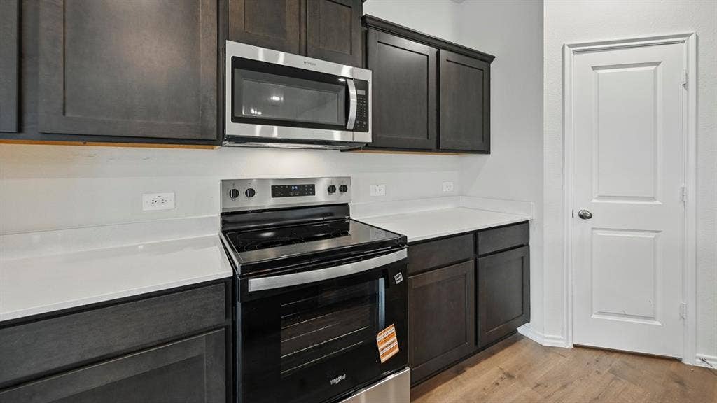 1928 Freeman Street, Tyler, TX 75704 Modern kitchen featuring dark wood-finish cabinetry, stainless steel microwave, black electric range, white countertops, and wood-finish flooring