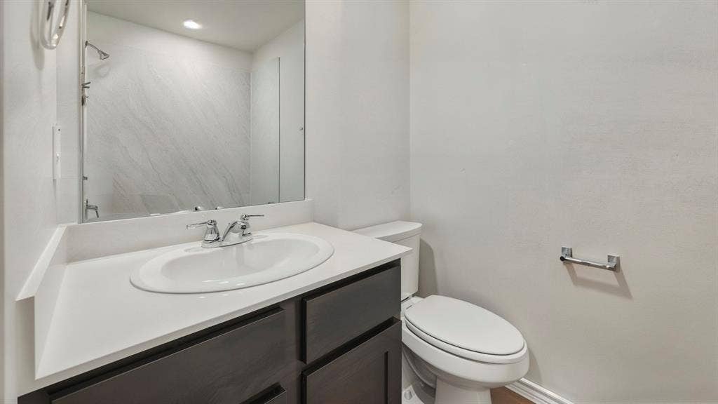 1928 Freeman Street, Tyler, TX 75704 Bathroom featuring a vanity with an integrated sink, a large wall-mounted mirror, a two-piece toilet, and a chrome towel bar