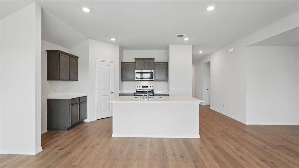 1924 Freeman Street, Tyler, TX 75704 Open-concept kitchen with a central island, dark wood-finish cabinetry, white countertops, built-in microwave, and recessed lighting