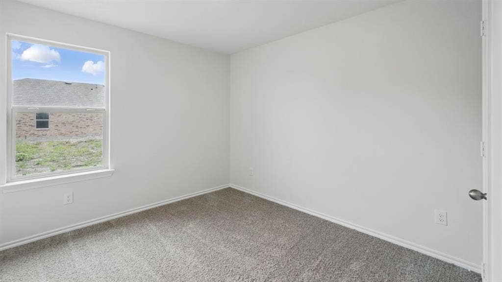 1924 Freeman Street, Tyler, TX 75704 Neutral-toned bedroom featuring a single window with white trim, light gray wall paint, and gray carpet flooring