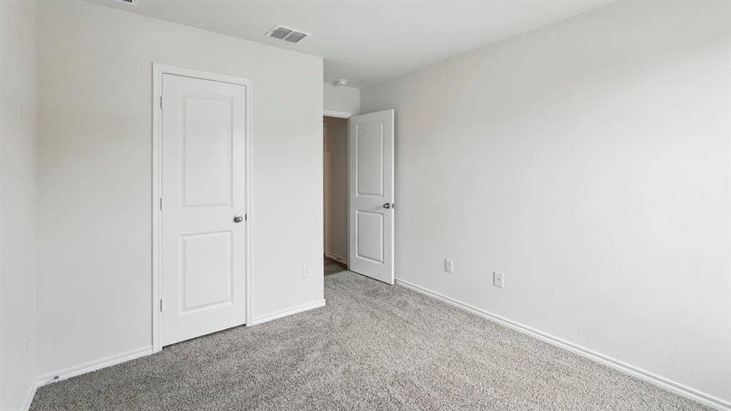1924 Freeman Street, Tyler, TX 75704 White-painted interior room featuring gray carpet flooring, white baseboards, and a white two-panel door with a silver knob