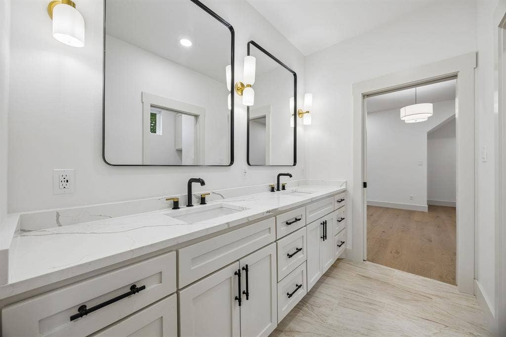 3027 Brooklyndell Avenue, Dallas, TX 75211 Dual vanity with white cabinetry, matte black hardware, integrated sinks, and polished countertops
