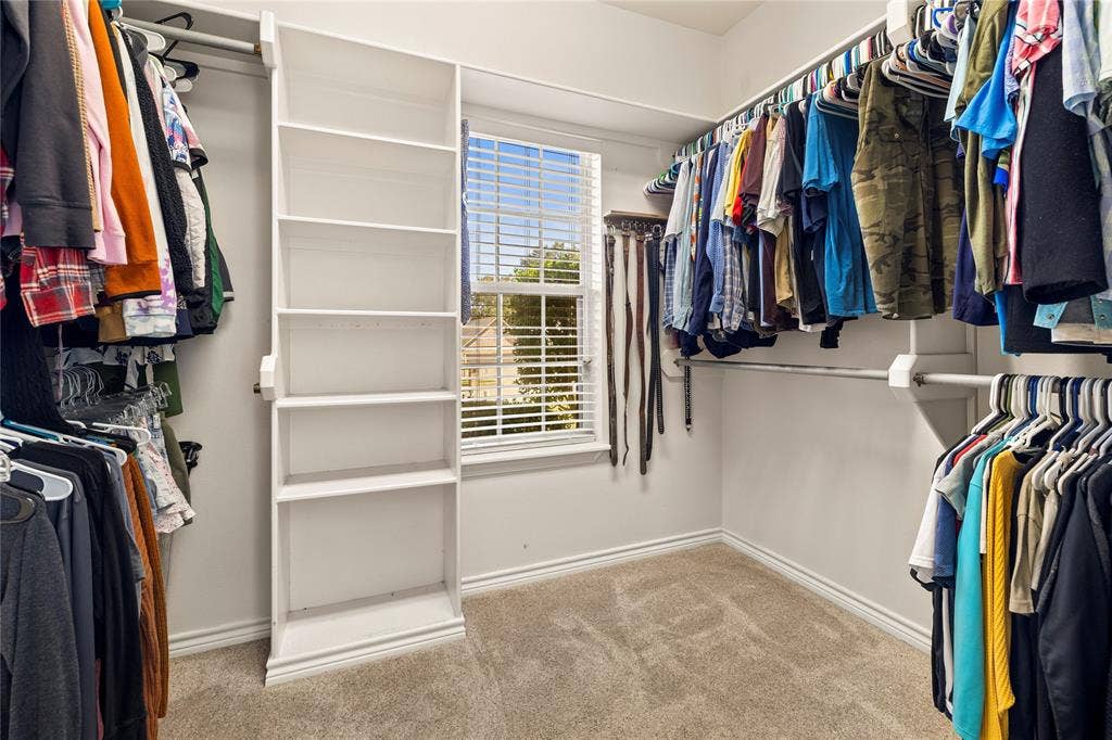 618 Huntwick Lane, Tyler, TX 75703 Walk-in closet with carpet flooring, built-in shelving, hanging rods, and a window with horizontal blinds