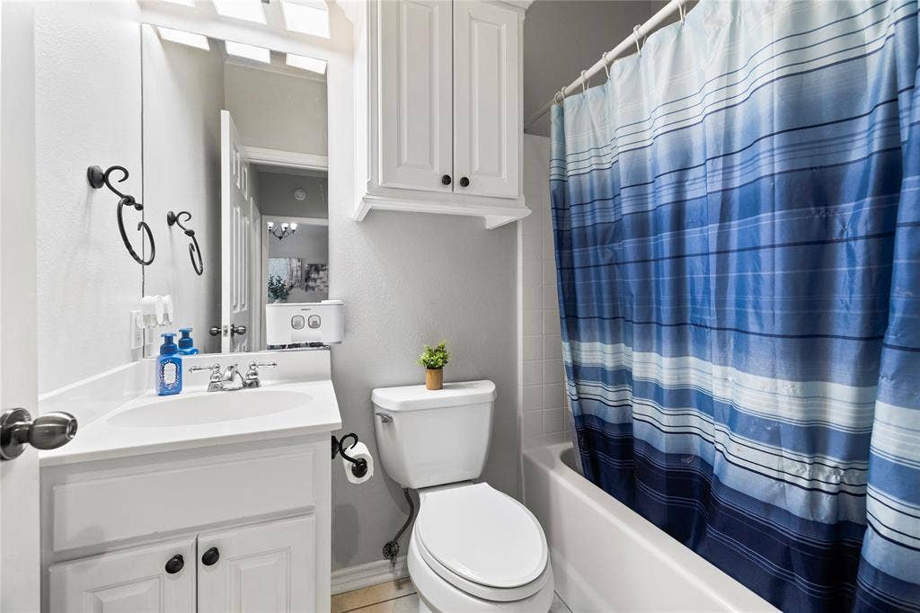 618 Huntwick Lane, Tyler, TX 75703 Vanity with integrated sink, white cabinetry, wall-mounted mirror, built-in shelving, and white bathtub
