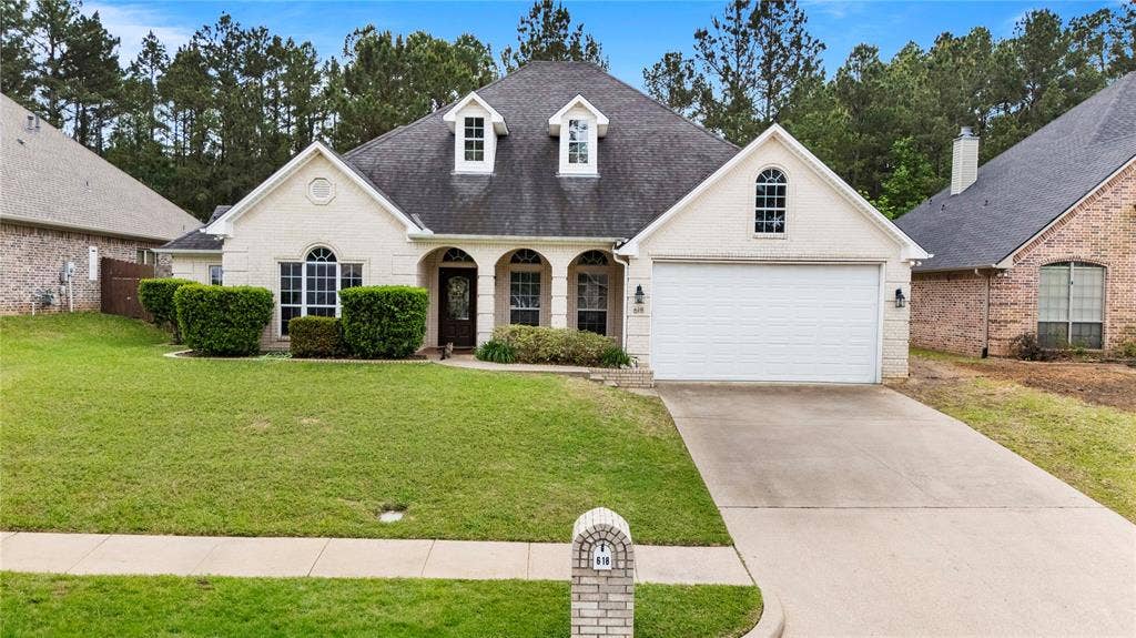 618 Huntwick Lane, Tyler, TX 75703 Cream brick exterior with dark shingle roof and dormer windows