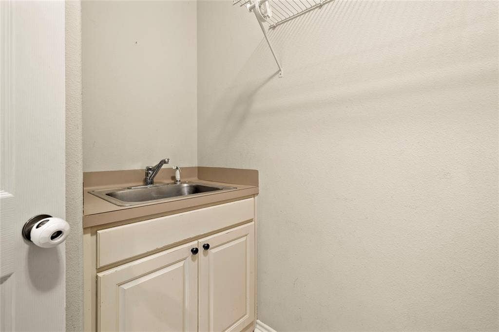 618 Huntwick Lane, Tyler, TX 75703 Utility sink with a chrome faucet, light-toned countertop, and white cabinetry