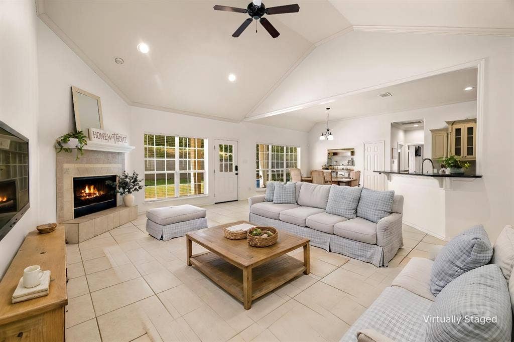 618 Huntwick Lane, Tyler, TX 75703 Vaulted ceilings, a stone-clad fireplace, large grid-pane windows, light tile flooring, and an open-concept pass-through kitchen