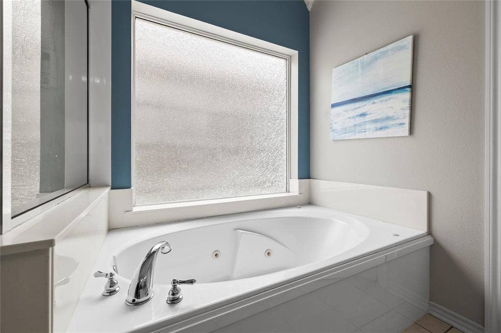 618 Huntwick Lane, Tyler, TX 75703 Corner jetted tub with polished chrome fixtures and a frosted window