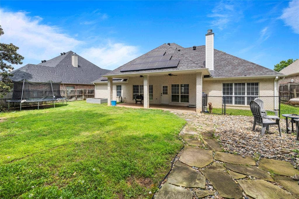 618 Huntwick Lane, Tyler, TX 75703 Expansive backyard featuring a covered patio, solar panels, and a stone walkway