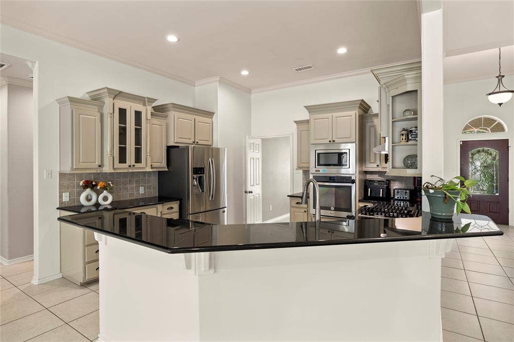 618 Huntwick Lane, Tyler, TX 75703 Kitchen featuring dark countertops, light-toned cabinetry, stainless steel appliances, and a tiled backsplash