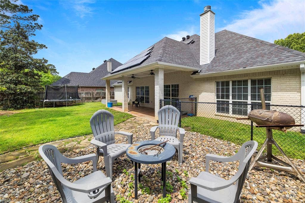 618 Huntwick Lane, Tyler, TX 75703 Expansive backyard featuring a stone patio, fire pit, covered porch with recessed lighting, and a manicured lawn