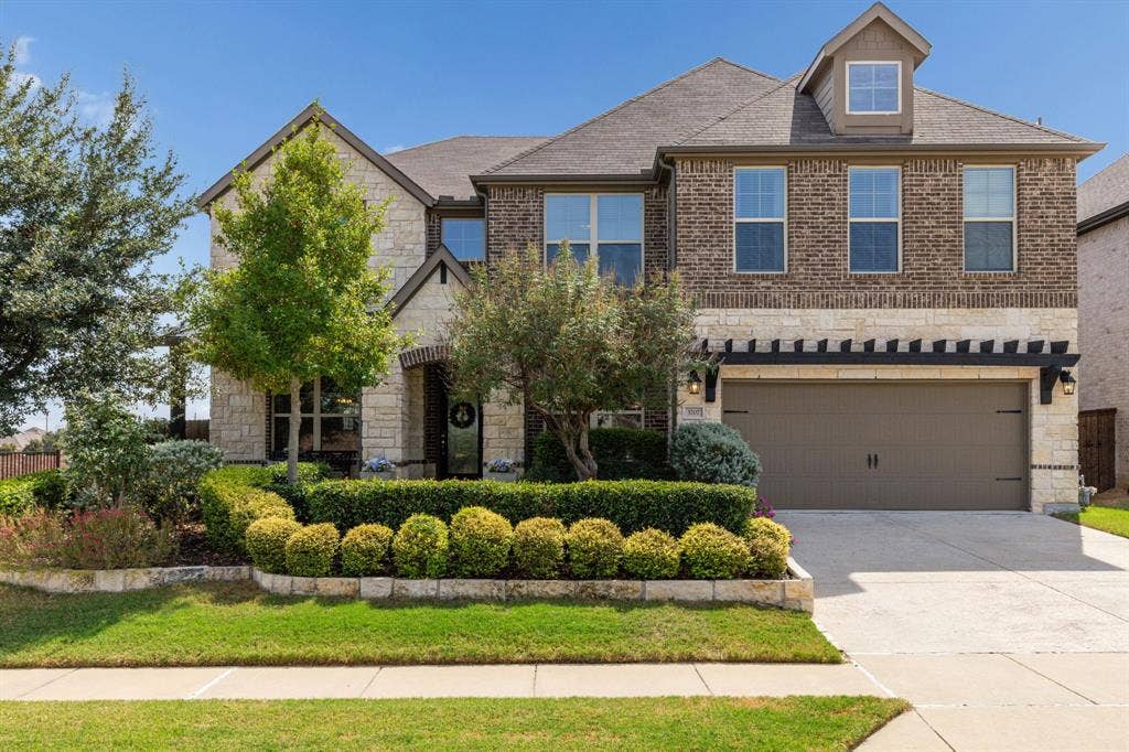 3707 Roth Drive, McKinney, TX 75071 Striking curb appeal showcases the home’s refined brick and natural stone façade, distinctive architectural detailing, manicured landscaping, and welcoming covered entry.