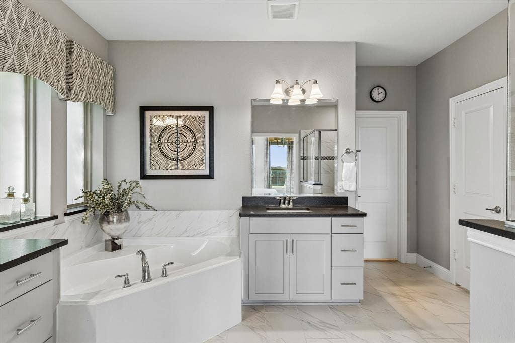 3707 Roth Drive, McKinney, TX 75071 Spa-inspired primary bath features a generous soaking tub, dual vanity, abundant cabinetry, framed mirror, and soft designer-inspired finishes.
