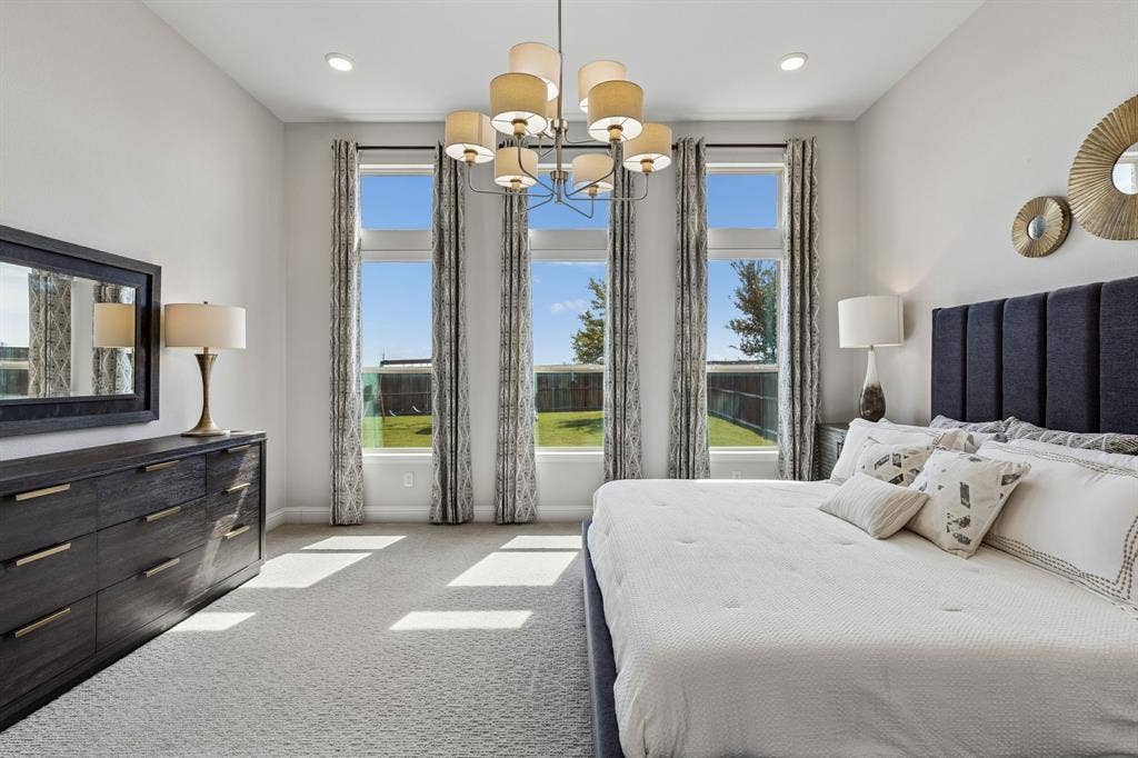 3707 Roth Drive, McKinney, TX 75071 Expansive primary bedroom showcases dramatic floor-to-ceiling-style windows, abundant natural light, plush carpeting, and an inviting palette designed for relaxed sophistication.