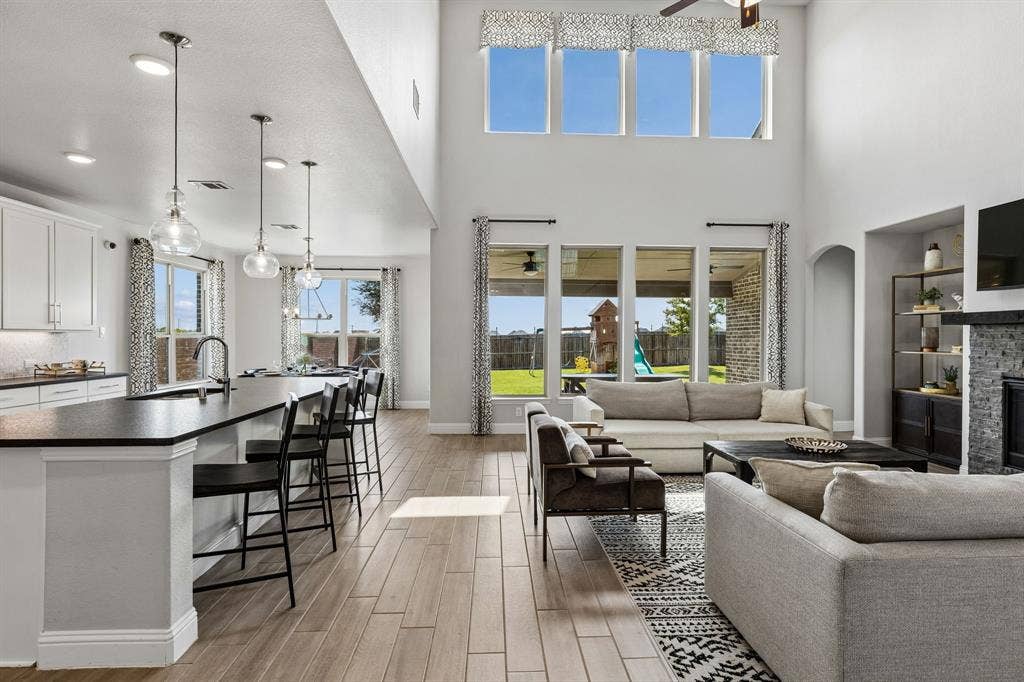 3707 Roth Drive, McKinney, TX 75071 Impressive open-concept living space seamlessly connects the living room and kitchen, highlighted by soaring ceilings, expansive windows, abundant natural light, and effortless views toward the backyard.
