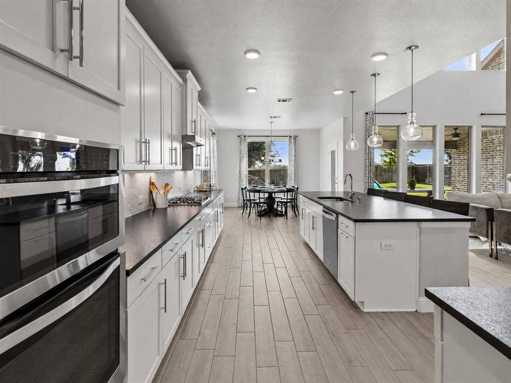3707 Roth Drive, McKinney, TX 75071 Bright and beautifully appointed kitchen opens naturally toward the breakfast and living spaces, creating a seamless everyday gathering area with extensive cabinetry, pendant lighting, and generous prep surfaces.