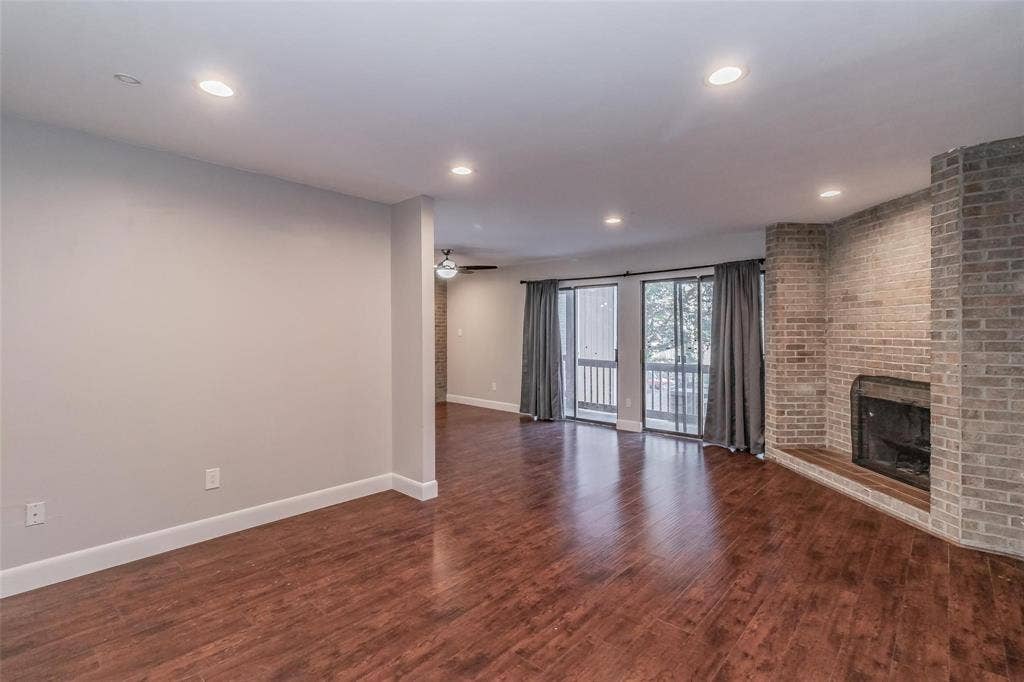 4930 Thunder Road, Dallas, TX 75244 Hardwood-finish flooring throughout, recessed lighting, brick fireplace with hearth, and sliding glass doors with balcony access