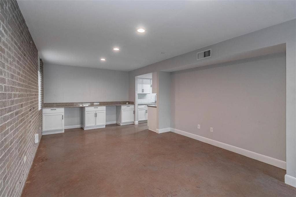 4930 Thunder Road, Dallas, TX 75244 Exposed brick accent wall, recessed lighting, built-in cabinetry with stone countertops, concrete-finish flooring, and white baseboards