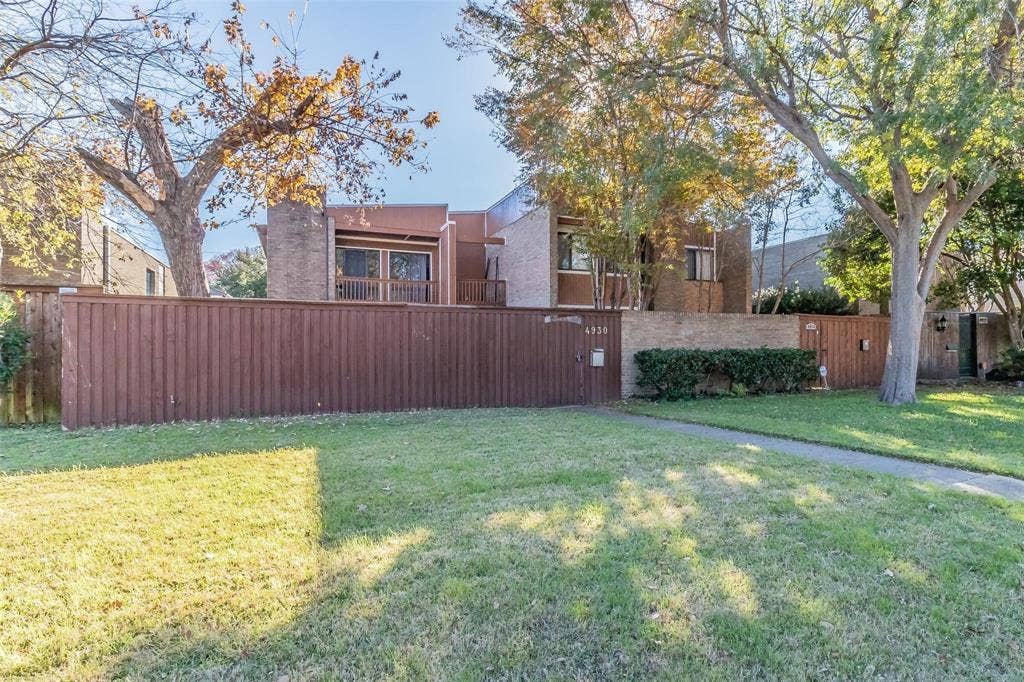 4930 Thunder Road, Dallas, TX 75244 Brick-clad exterior with a private balcony, wood fence, and mature trees
