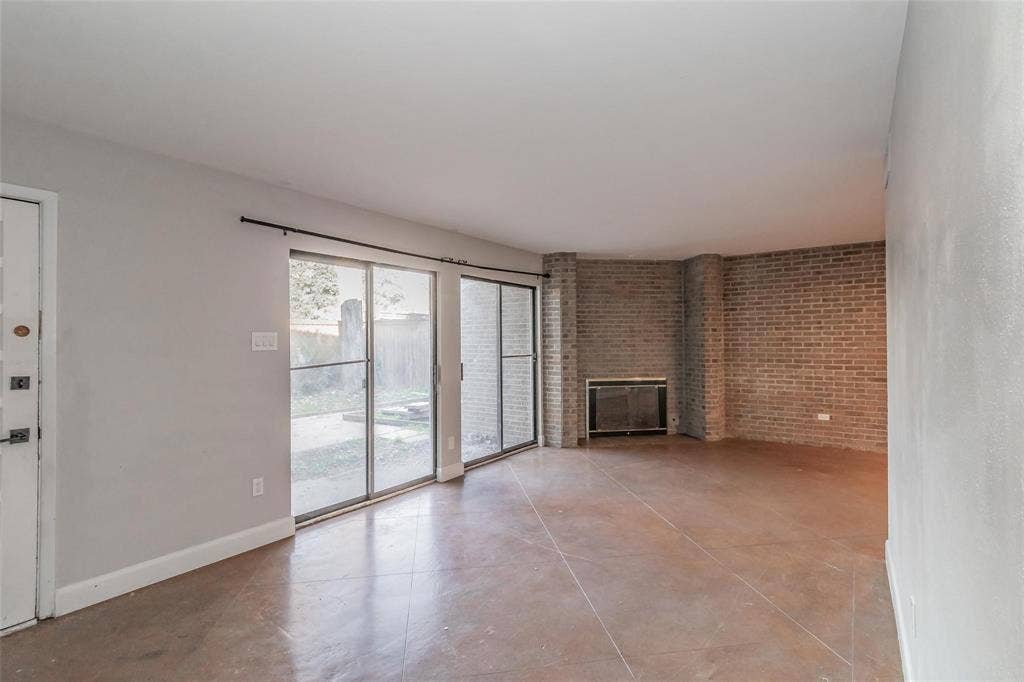 4930 Thunder Road, Dallas, TX 75244 Spacious living area featuring a brick fireplace, sliding glass doors, and durable tile flooring