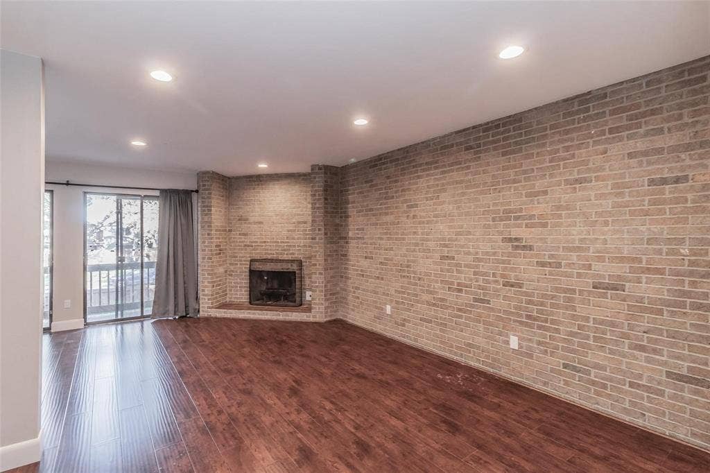 4930 Thunder Road, Dallas, TX 75244 Wood-finish flooring, recessed lighting, brick accent wall, built-in fireplace, and sliding glass doors to outdoor space