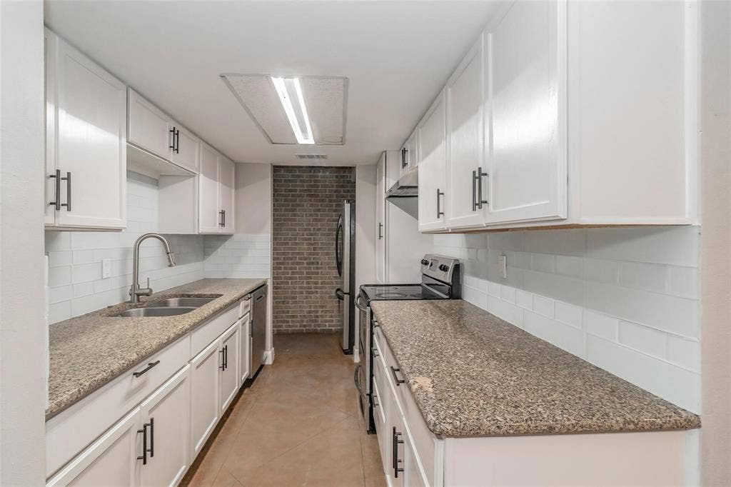 4930 Thunder Road, Dallas, TX 75244 Galley kitchen featuring white cabinetry with dark hardware, stone-finish countertops, subway tile backsplash, and stainless steel appliances