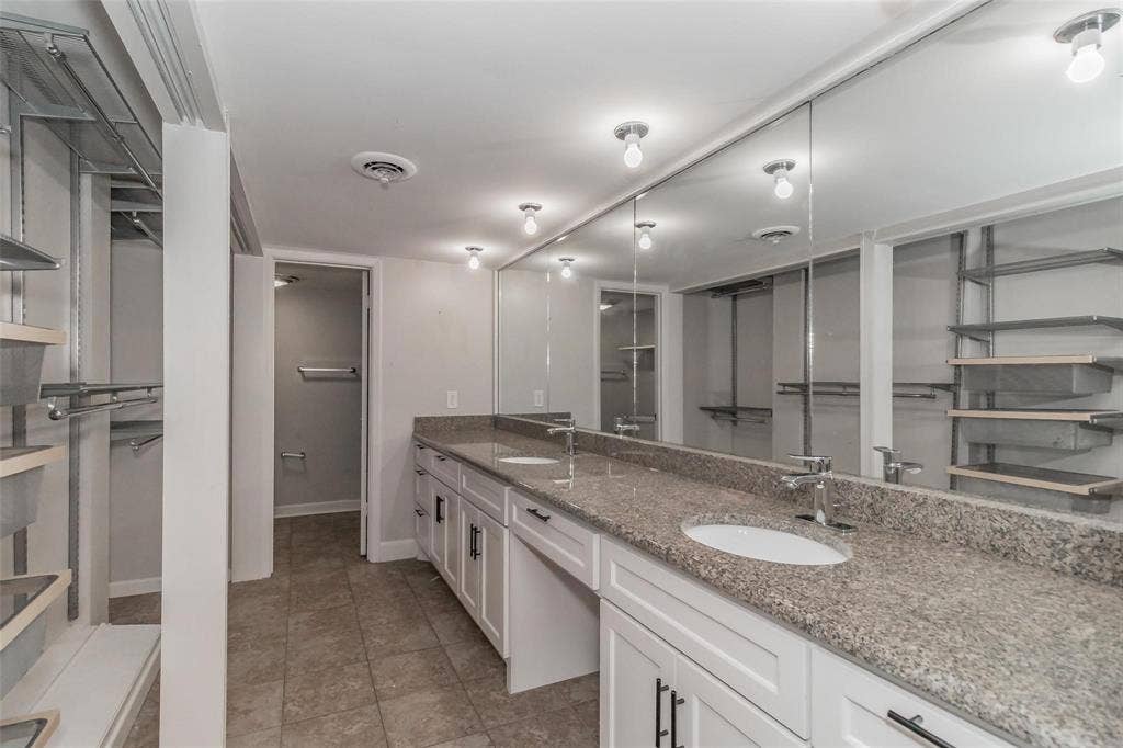 4930 Thunder Road, Dallas, TX 75244 Expansive dual vanity with a patterned countertop, dual undermount sinks, and white cabinetry with dark hardware
