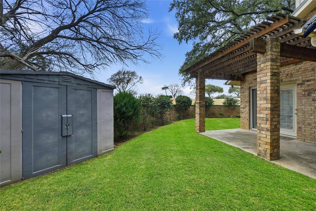 4424 Westridge Avenue, Fort Worth, TX 76116 Expansive lawn area with a stone-clad pergola, attached storage shed, and mature perimeter landscaping