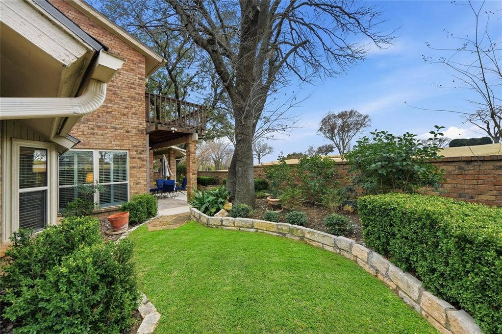 4424 Westridge Avenue, Fort Worth, TX 76116 Brick exterior featuring multiple windows, a second-story wooden balcony, and a ground-level patio