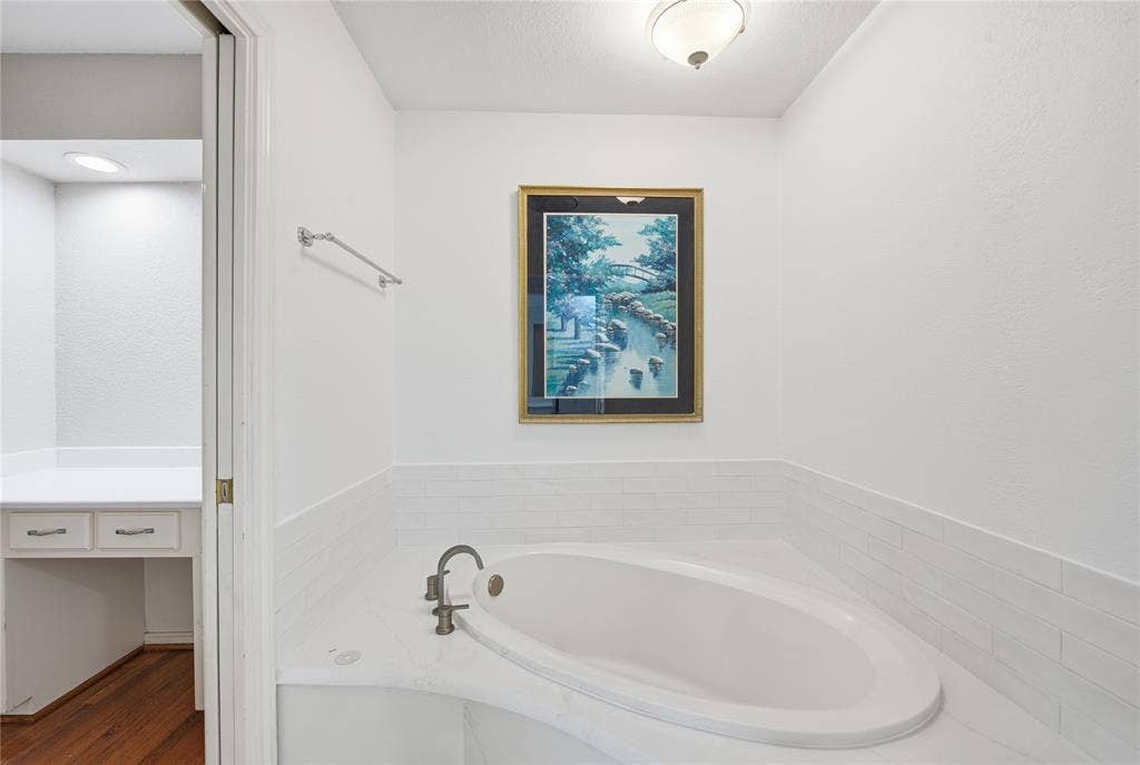 4424 Westridge Avenue, Fort Worth, TX 76116 Built-in soaking tub with corner placement, white tile surround, and a deck-mounted faucet