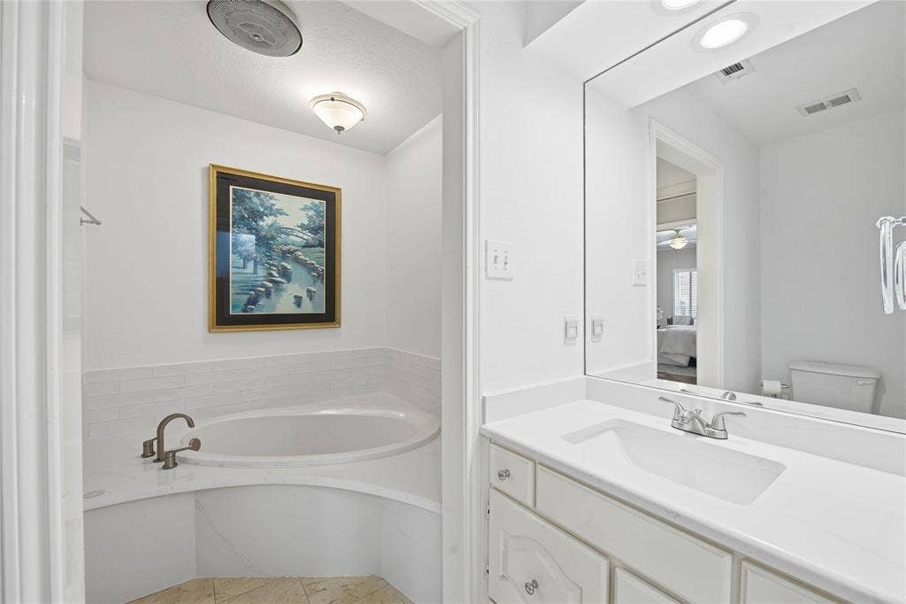 4424 Westridge Avenue, Fort Worth, TX 76116 Corner soaking tub with subway tile surround, single vanity with integrated sink, and large wall-mounted mirror