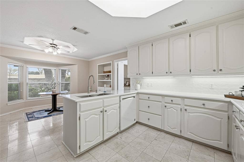 4424 Westridge Avenue, Fort Worth, TX 76116 White cabinetry, under-cabinet lighting, tiled flooring, bay windows, and a built-in kitchen island with a sink