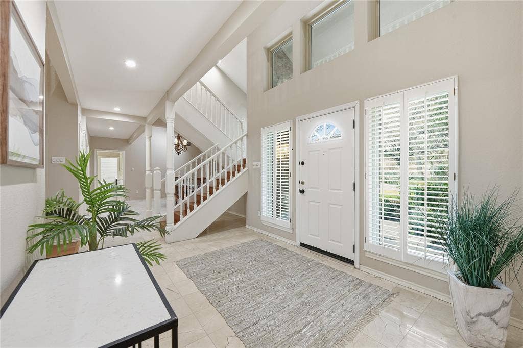 4424 Westridge Avenue, Fort Worth, TX 76116 Foyer featuring a white paneled entry door with an arched transom, sidelight windows with plantation shutters, a grand staircase with white balusters, and tile flooring